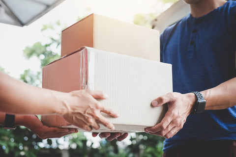 A man passing a cardboard box to another person.